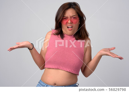 Young confused Asian woman with heart shaped glasses shrugging shoulders Young confused Asian woman with heart shaped glasses shrugging shoulders 56829798