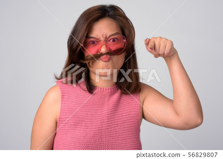 Young angry Asian woman with hair as mustache pointing at camera Young angry Asian woman with hair as mustache pointing at camera 56829807