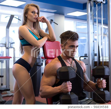 Guy exercising and his girlfriend standing next 56834588