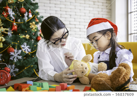 Mother play with her daughter with teddy bear on 56837609
