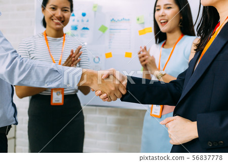 Young business people shaking hands and cheering crowd clapping background Young business people shaking hands and cheering crowd clapping background 56837778