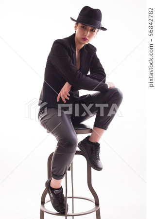 Caucasian beauty with a stylish hat sitting on a chair over white background in studio Caucasian beauty with a stylish hat sitting on a chair over white background in studio 56842782