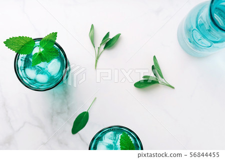 Top view of two beautiful vintage turquoise glasses and a bottle with cold drink and ice cubes 56844455