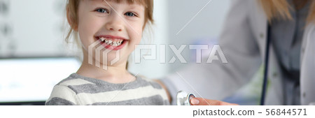 Smiling cute little girl with doctor measuring heart beat with stethoscope 56844571
