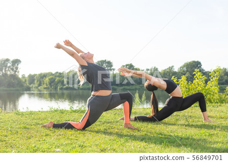 Healthy lifestyle and people concept - Flexible women doing yoga in the summer park Healthy lifestyle and people concept - Flexible women doing yoga in the summer park 56849701