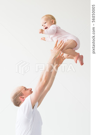 Father lifting baby girl. Happy father picks up and throws his lifting a small child. Home 56850005