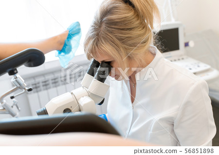 A gynecologist examines a patient on a 56851898