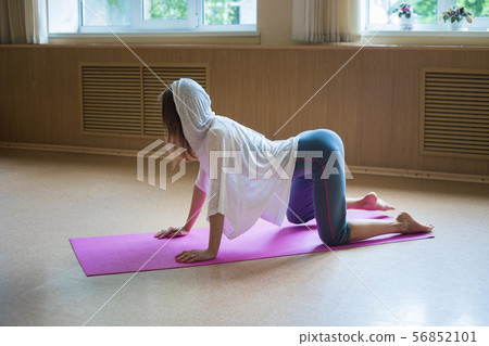 Young woman exercising on the yoga mat standing in her knees - performing an exercising for the loin Young woman exercising on the yoga mat standing in her knees - performing an exercising for the loin 56852101