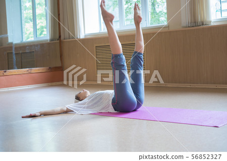 Young slim woman with blonde hair lying on the floor with her legs up 56852327