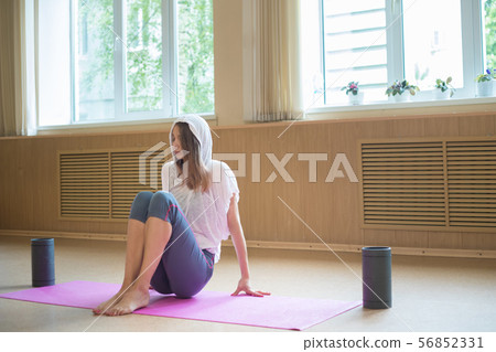 Young slim woman sitting on the yoga mat in dance studio 56852331