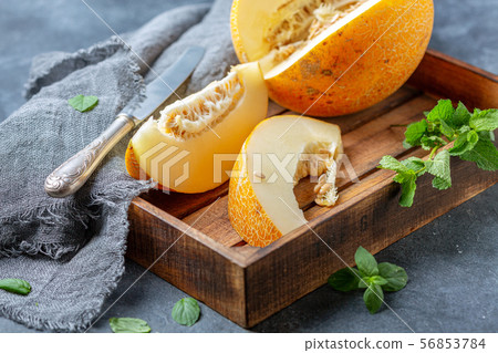 Slices of ripe yellow melon in a wooden tray. 56853784