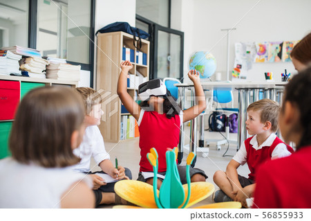 A group of small school kids with VR goggles sitting on the floor in class. A group of small school kids with VR goggles sitting on the floor in class. 56855933