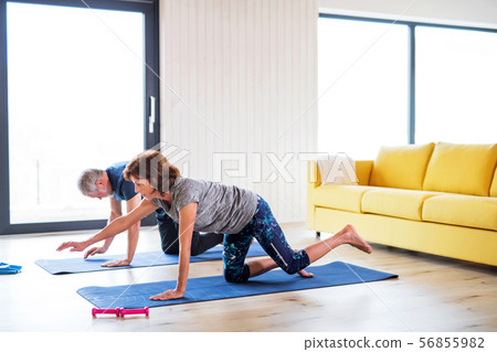 A senior couple indoors at home, doing exercise on the floor. A senior couple indoors at home, doing exercise on the floor. 56855982