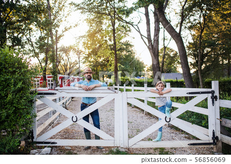 A portrait of father with small daughter outdoors on family farm. A portrait of father with small daughter outdoors on family farm. 56856069