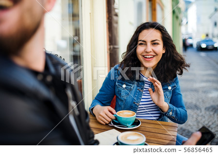 Young friends sitting in an outdoor cafe, talking. 56856465