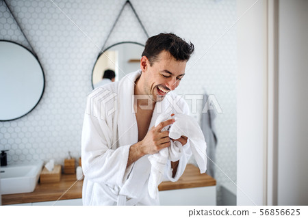 Young man with bathrobe laughing in the bedroom, a morning routine. Young man with bathrobe laughing in the bedroom, a morning routine. 56856625