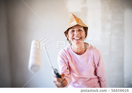 Senior woman painting walls in new home, having fun. Relocation concept. Senior woman painting walls in new home, having fun. Relocation concept. 56856626
