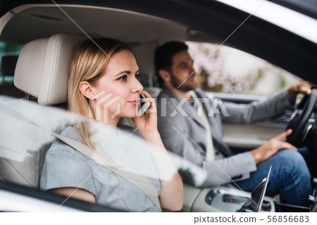 Happy young couple sitting in car, making phone call. 56856683