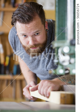 Craftsman using bandsaw for splitting wood plank in workshop 56856724