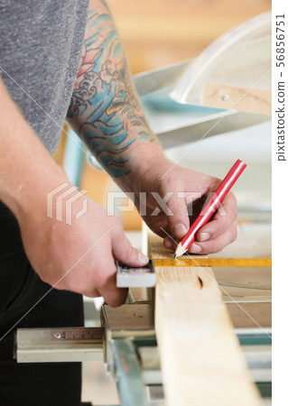 Carpenter measures length of a wood plank before sawing 56856751