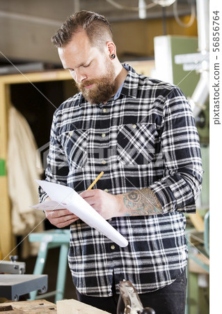 Carpenter writing at drawings in the workshop 56856764