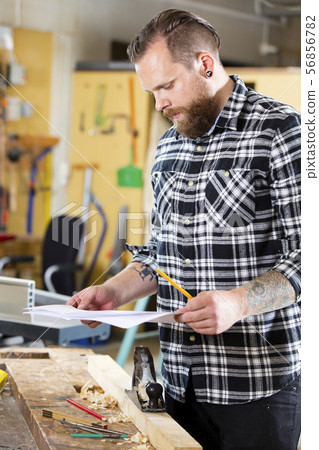 Carpenter planning work and looking at drawings in the workshop Carpenter planning work and looking at drawings in the workshop 56856782
