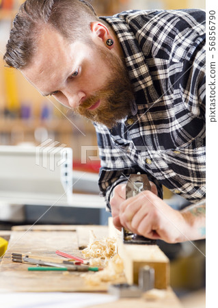 Carpenter work with planer on wood plank in workshop 56856790