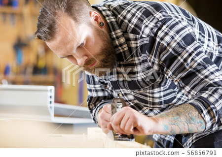 Carpenter work with plane on wood plank in workshop 56856791