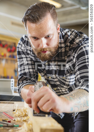 Carpenter work with plane on wood plank in workshop 56856809
