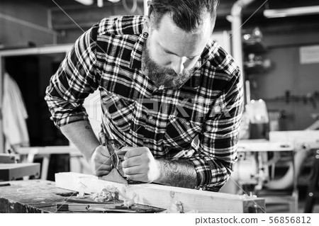 Carpenter work with plane on wood plank in workshop 56856812