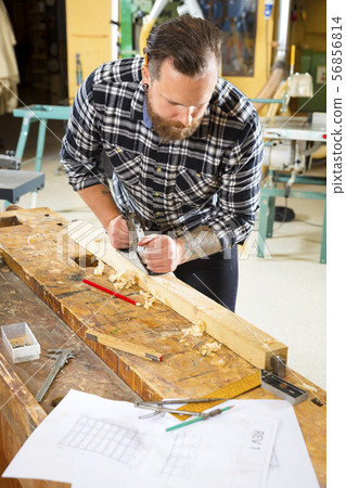 Above view of carpenter work with plane on wood plank in workshop 56856814