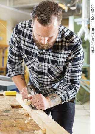 Carpenter work with plane on wood plank in workshop Carpenter work with plane on wood plank in workshop 56856844