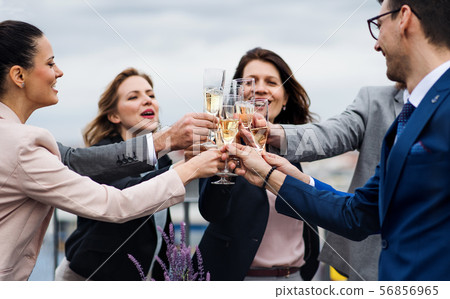 A group of joyful businesspeople having a party outdoors on roof terrace in city. 56856965