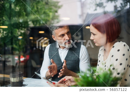 Man and woman having business meeting in a cafe, using tablet. Man and woman having business meeting in a cafe, using tablet. 56857122