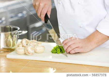 Professional chef cutting parley and mushrooms 56857378