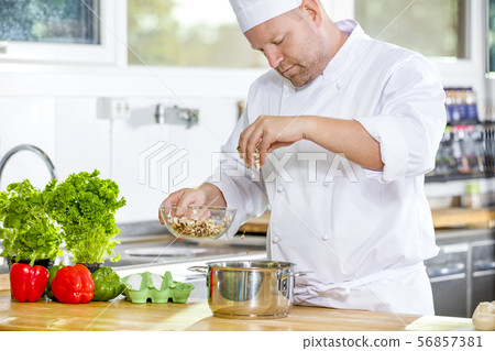 Professional chef preparing dish in large kitchen 56857381