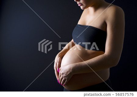 Pregnant woman with her hands on the bare belly Pregnant woman with her hands on the bare belly 56857576
