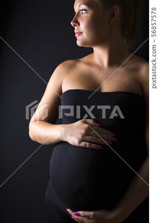 Beautiful pregnant woman stand with hands at the belly Beautiful pregnant woman stand with hands at the belly 56857578