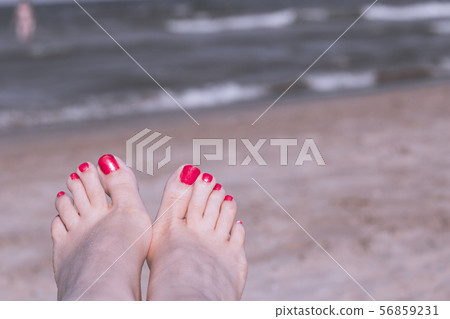 Feet of woman with nails painted red on the sand Feet of woman with nails painted red on the sand 56859231