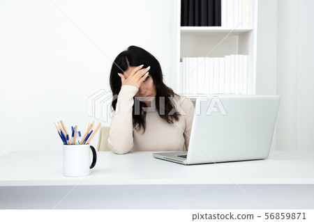 Sad and tired business woman working at the desk on the computer. Headache concept. Sad and tired business woman working at the desk on the computer. Headache concept. 56859871