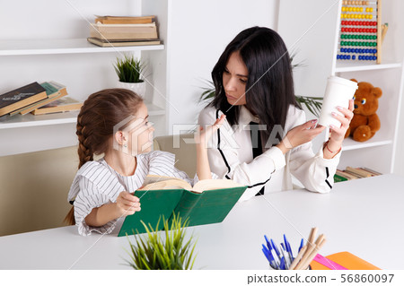 Pretty mother with cute daughter sitting with book in the room at home. 56860097