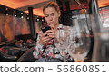 Young female French uses social networks to communicate with a mobile phone. Sits in a restaurant on 56860851