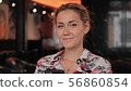 young female Frenchwoman looks at the camera happily and flirtatiously and smiles. Sits in a 56860854