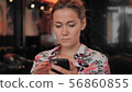 Caucasian young female uses smartphone while sitting in a restaurant. Slow Motion 56860855