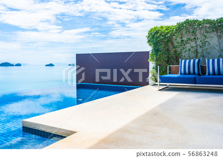 Beautiful luxury outdoor swimming pool with sea ocean view on blue sky white cloud around pillow on sofa decoration 56863248