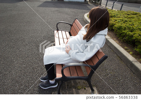 Pregnant woman resting on a bench 56863338