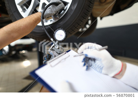 Serviceman inspects a pre-sale vehicle against Serviceman inspects a pre-sale vehicle against 56870801