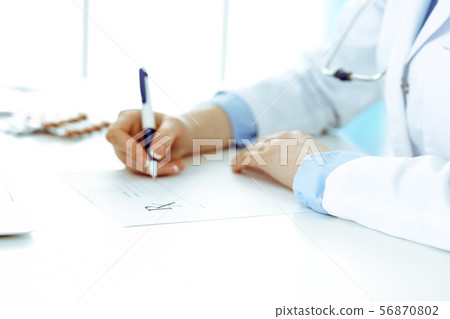 Female doctor filling up prescription form while sitting at the desk in hospital closeup. Healthcare 56870802