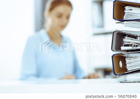 Binders with papers are waiting to be processed by business woman or bookkeeper back in blur Binders with papers are waiting to be processed by business woman or bookkeeper back in blur 56870840