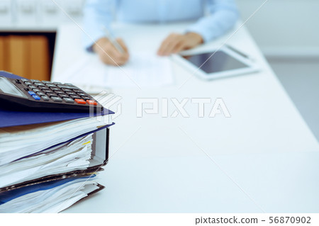 Calculator and binders with papers are waiting to be processed by business woman or bookkeeper back 56870902